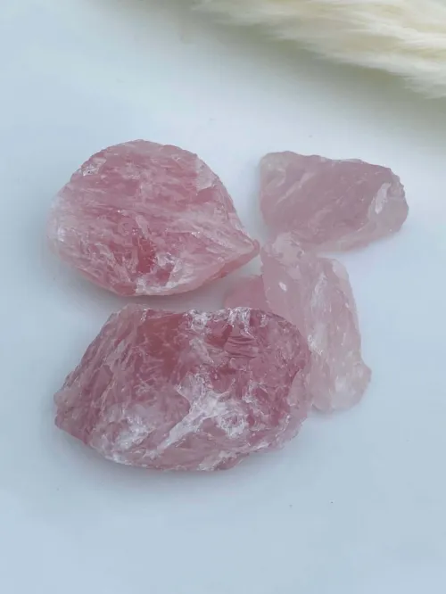 Rose quartz crystals arranged on a wooden desk next to meditation journal