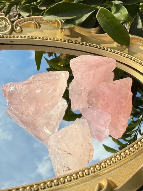 A hand gently cupping a piece of rose quartz outdoors