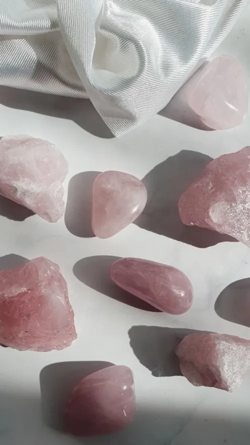 Close up of tumbled rose quartz stones in a hand near a morning window
