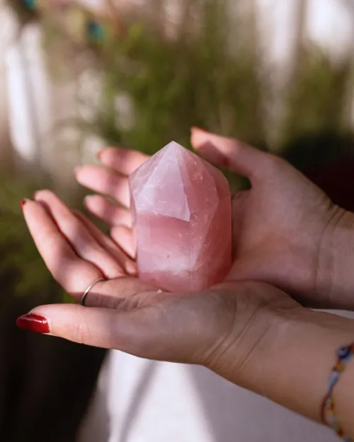 Hand wearing rose quartz bracelet layered with delicate chain for mindful style