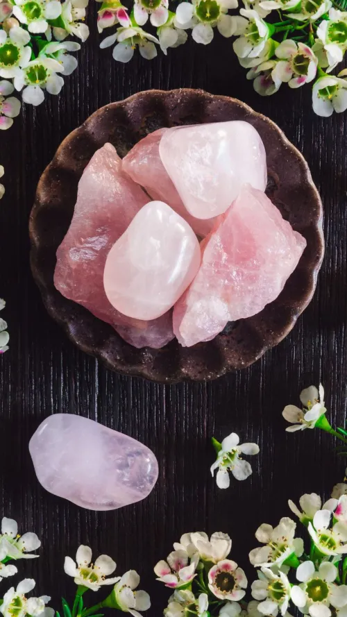 Person's hand holding rose quartz heart during meditation
