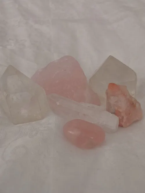 Rose quartz crystal and clear quartz point placed together on a wooden surface in natural light