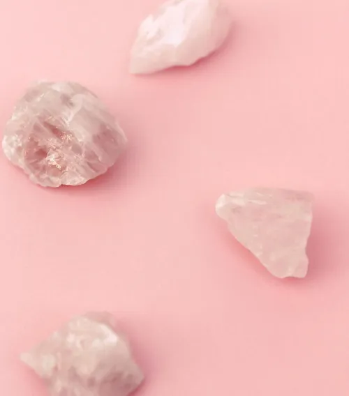 Rose quartz placed beside a bed with soft linen