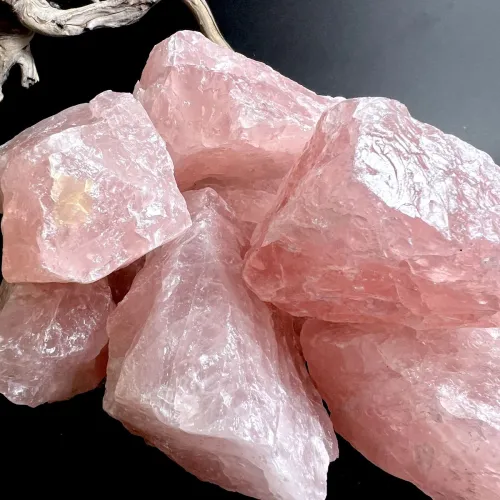 Several raw rose quartz crystals against natural backdrop