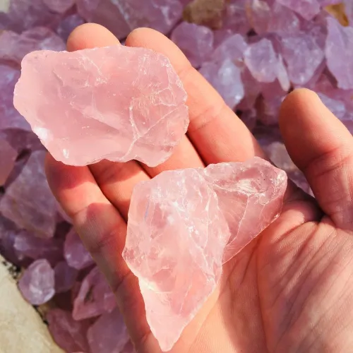 Tumbled rose quartz stones arranged on a wooden shelf